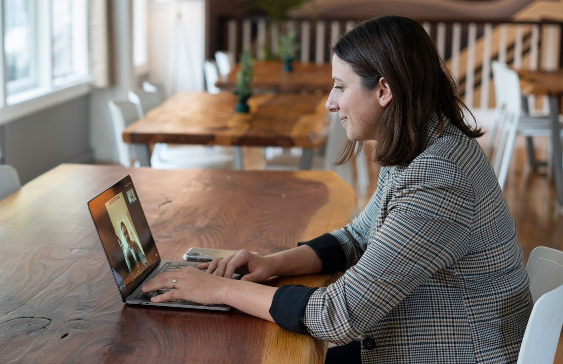  A woman video calling with someone on a laptop while sitting at the table.